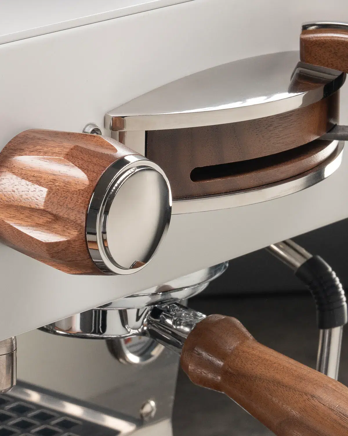 Walnut portafilter handle and matching wood-topped tamper on a white espresso machine