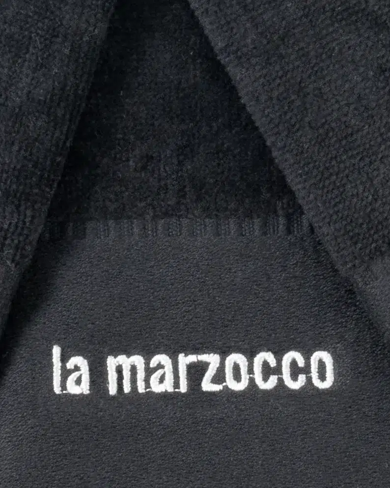 White la marzocco embroidery on a folded black barista towel