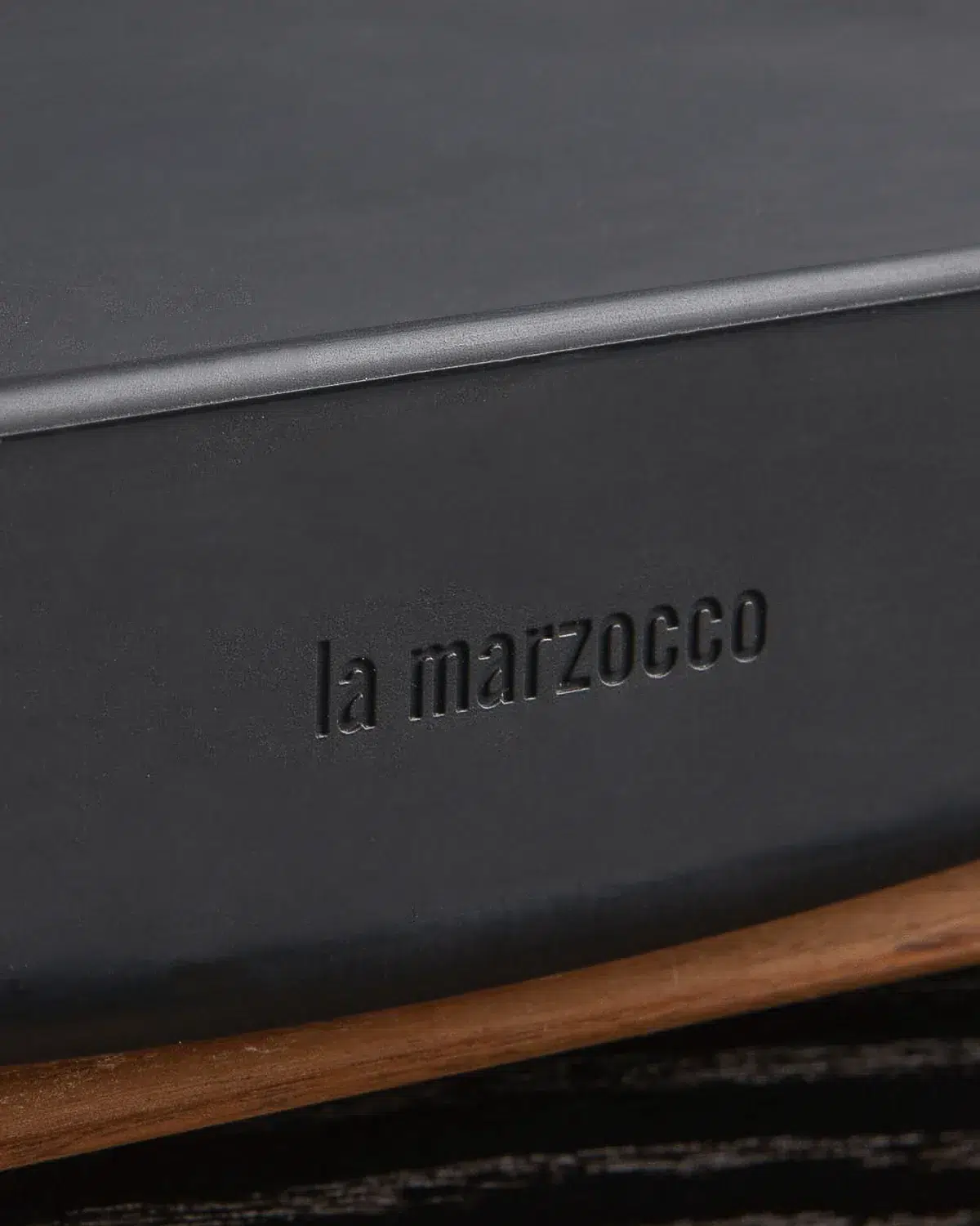 Embossed la marzocco wordmark on the edge of the black tamping mat, above a walnut base