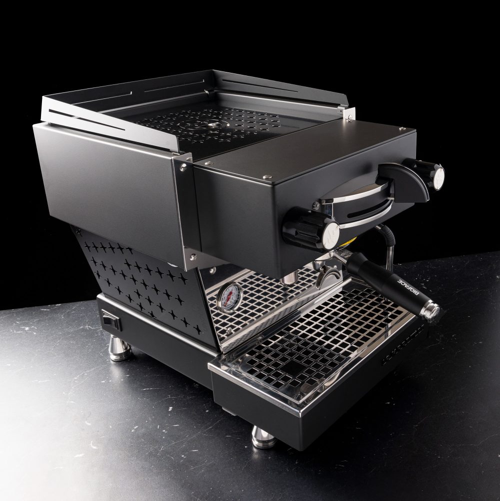 Custom black BIGFACE La Marzocco Linea Mini espresso machine seen from the front three-quarter on a black surface