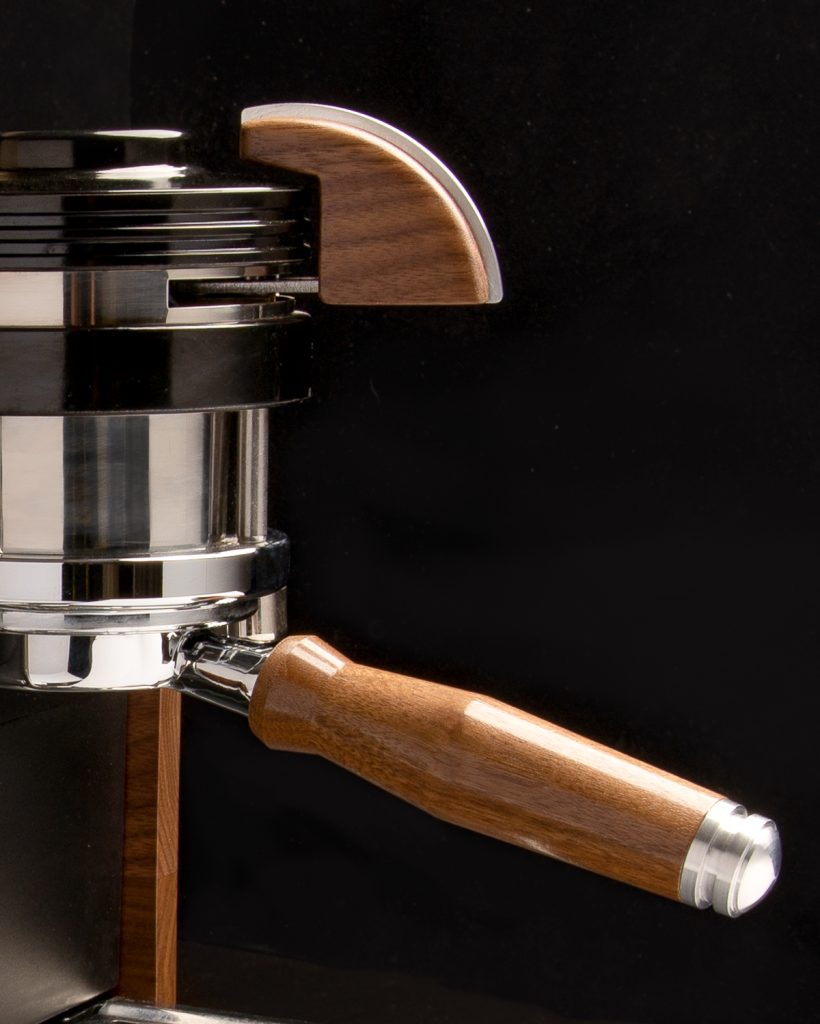 Close detail of a walnut accent above the group and a walnut portafilter handle on a La Marzocco GS3, against a black background