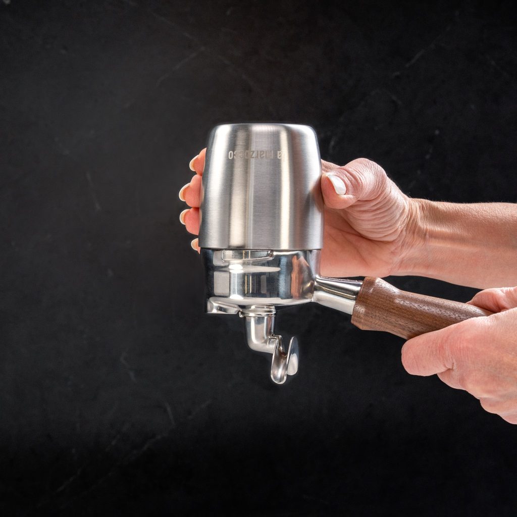Hands holding the La Marzocco double wall dosing cup fitted to a portafilter