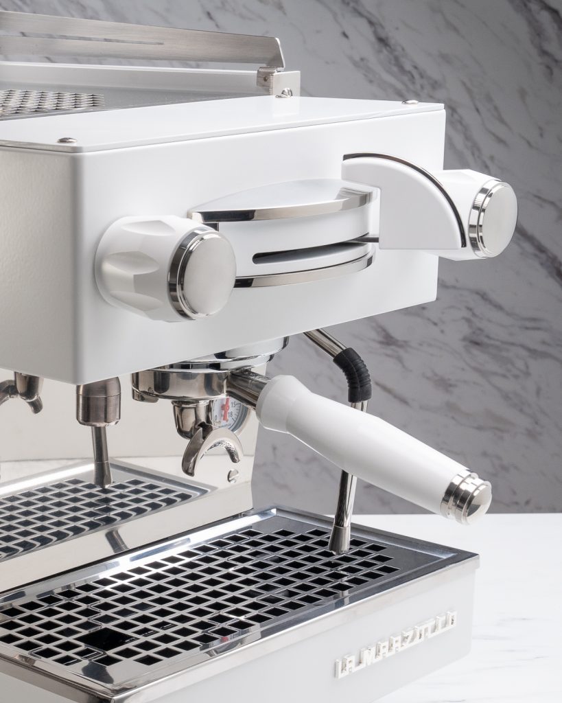 White steam knob, brew paddle, water knob and portafilter handle fitted to a white La Marzocco Linea Mini against marble