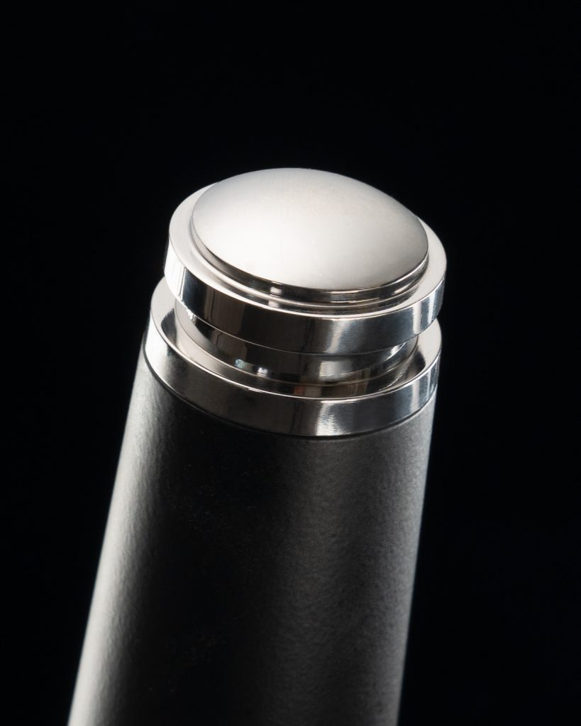 Close detail of the white end cap and chrome collar at the base of a black portafilter handle