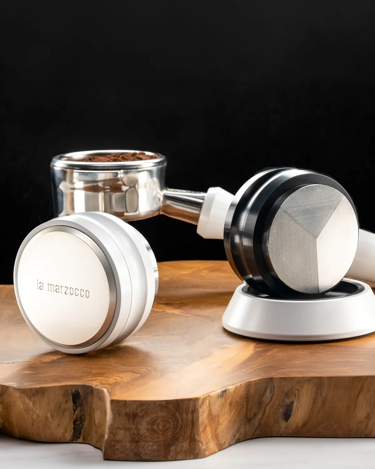 La Marzocco leveller, filled portafilter and tamper arranged on a live-edge wooden board