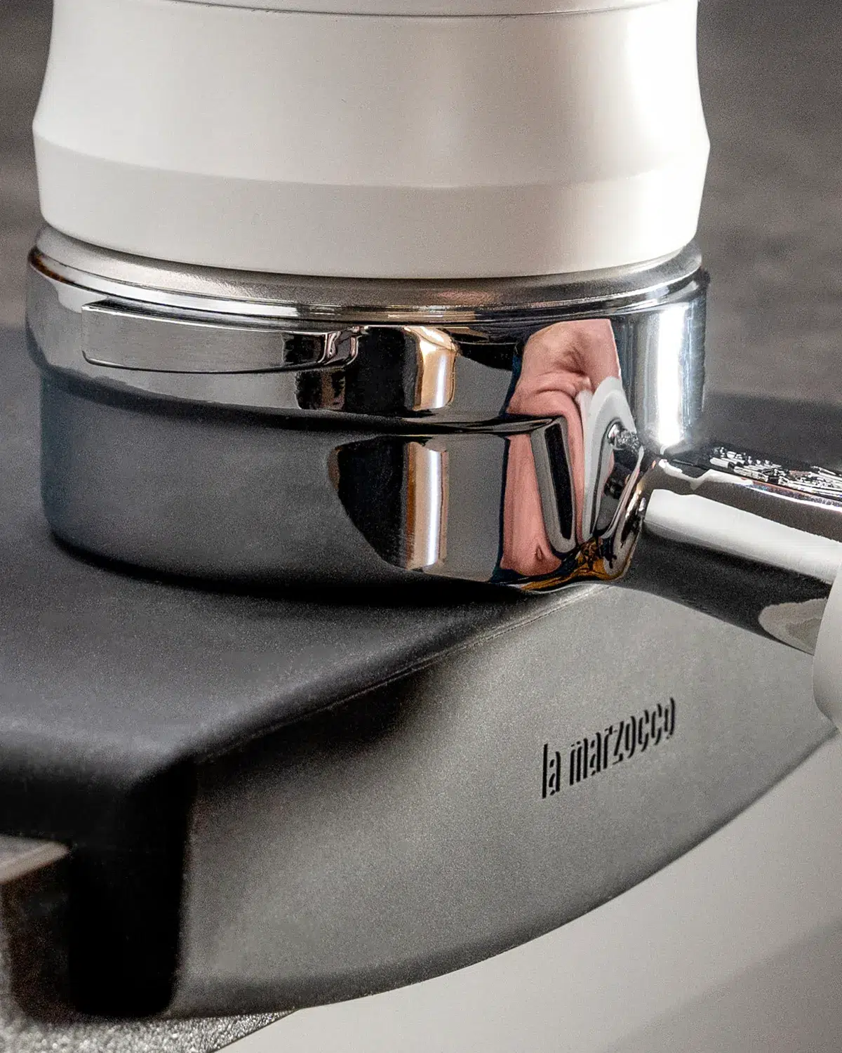 Portafilter resting in a black La Marzocco tamping mat on a white espresso machine
