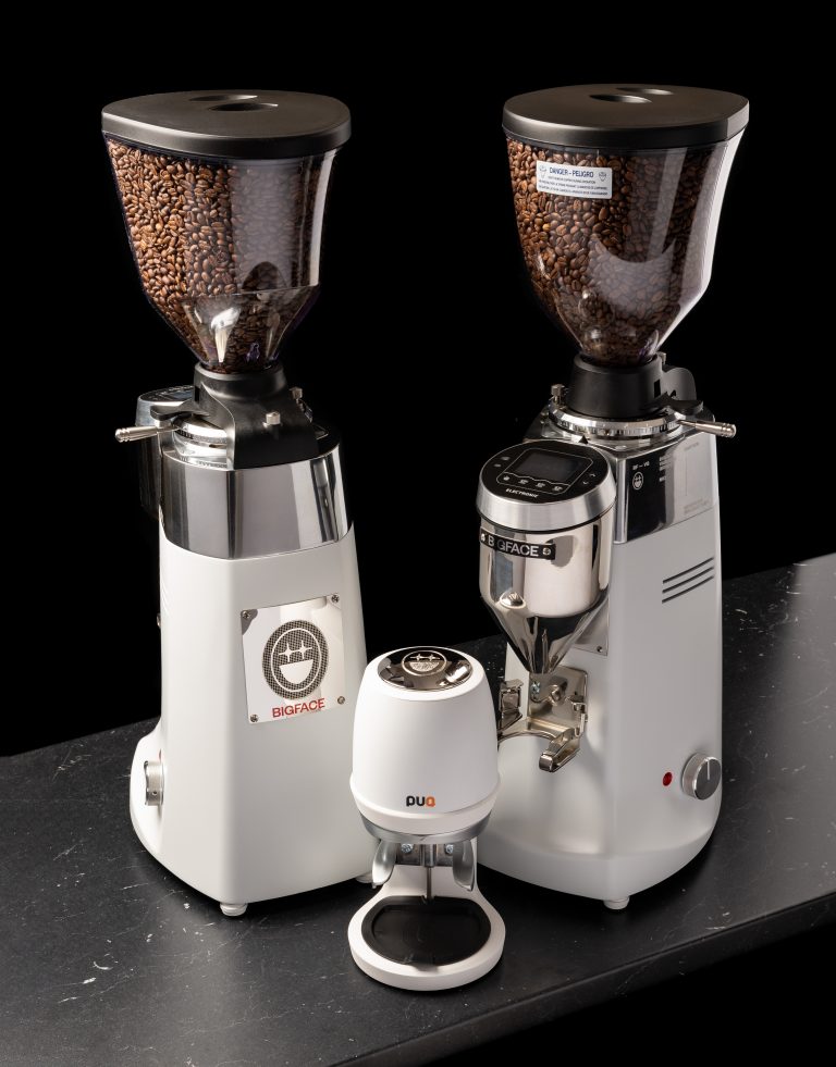 Two BIGFACE badged espresso grinders beside a white puq press tamper
