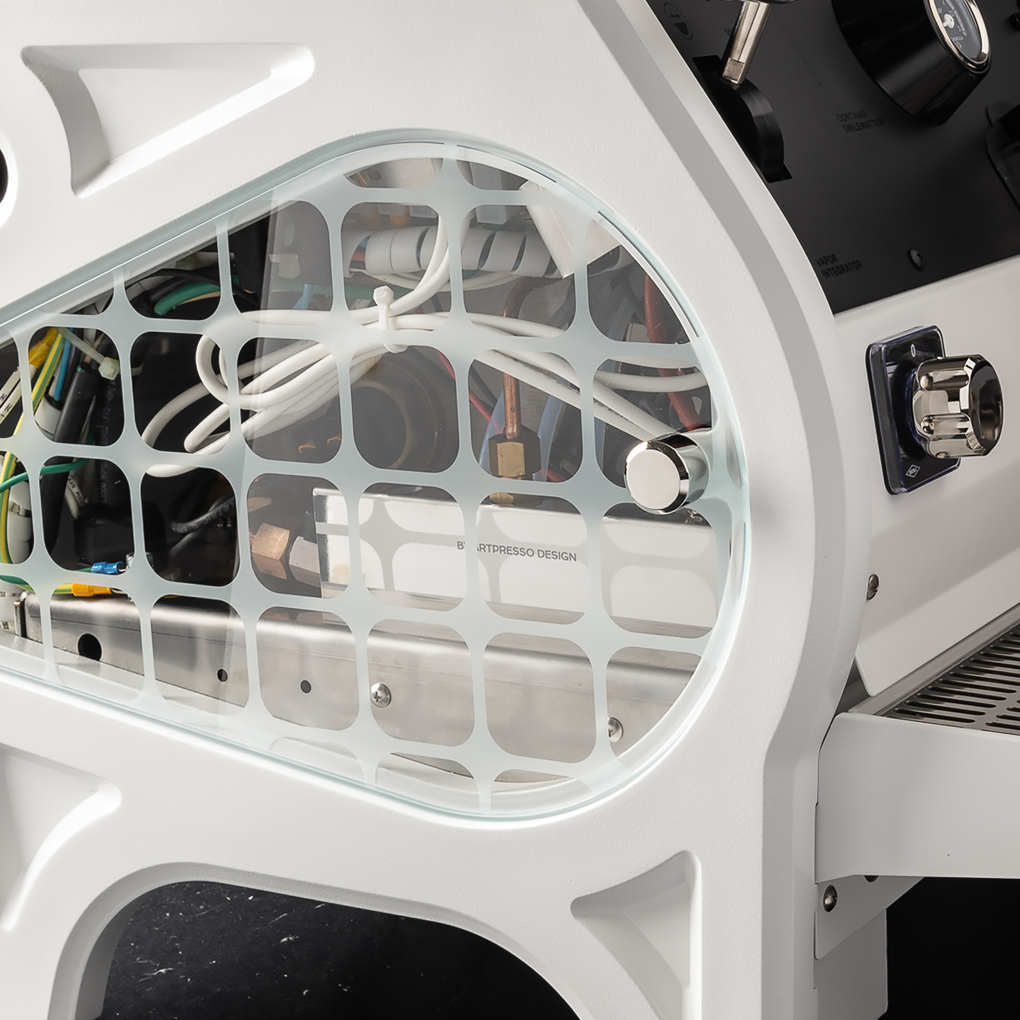 Close-up of a custom white espresso machine with a glass side panel revealing the internal plumbing and wiring, engraved By Artpresso Design