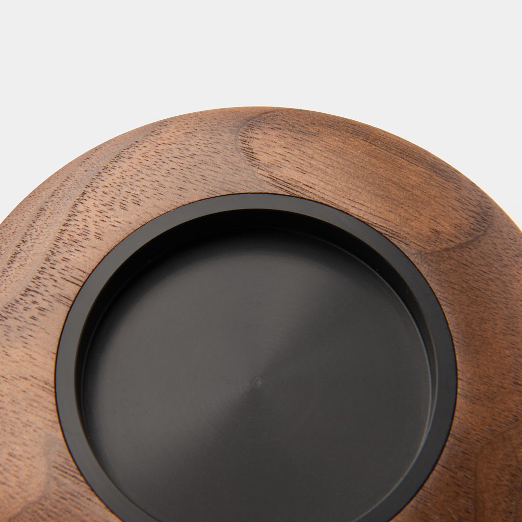 Close-up of the walnut Breville grinder and tamper holder cover showing its black recessed insert