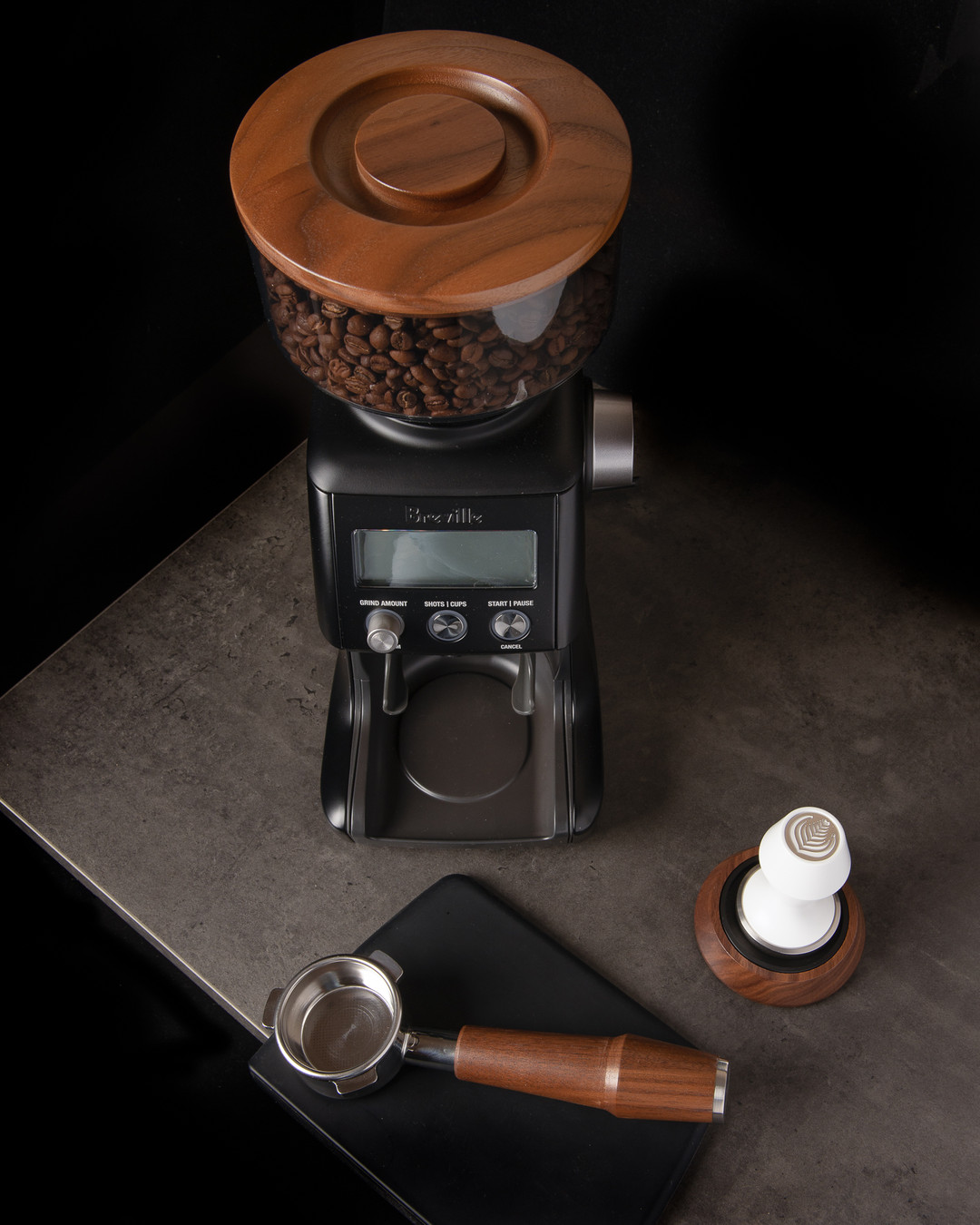 Breville grinder with a walnut hopper lid beside an Artpresso walnut handled portafilter and a white tamper on a walnut stand