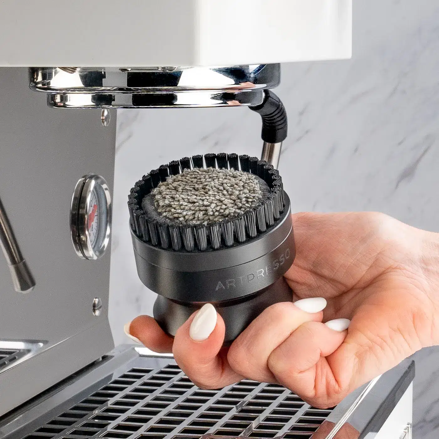 Group Head Pro Cleaning Tool with its nylon ring brush and microfiber pad, held under an espresso machine group head