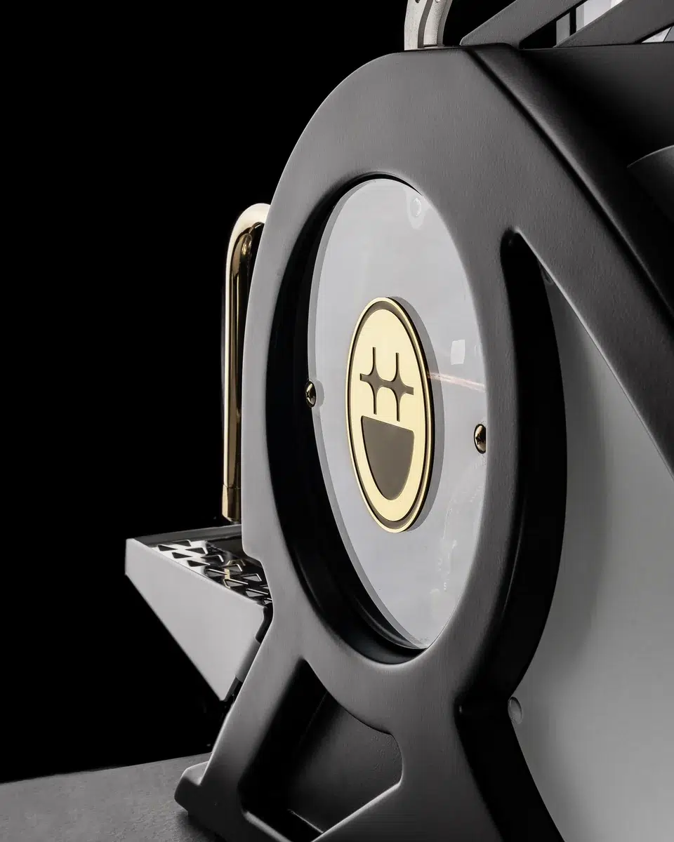 Round side window of the BIGFACE La Marzocco Leva with the gold BIGFACE medallion and brass handle