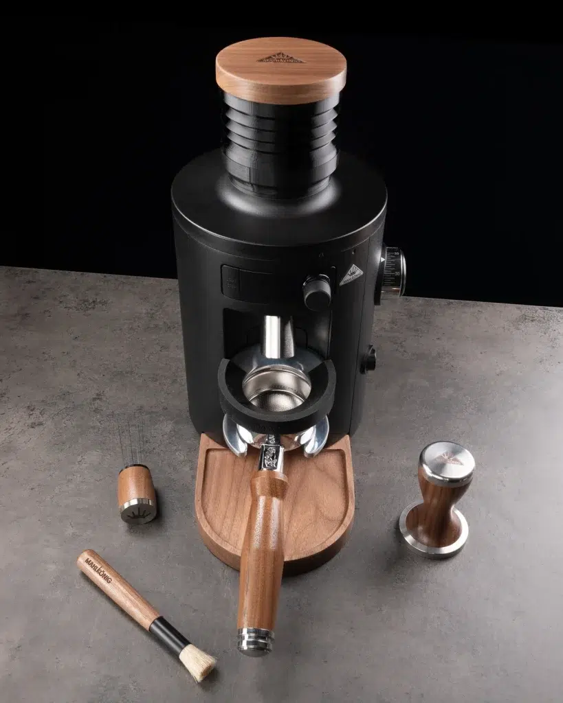Mahlkönig grinder on a dark counter with the walnut dosing tray, portafilter, distribution tool, brush and tamper